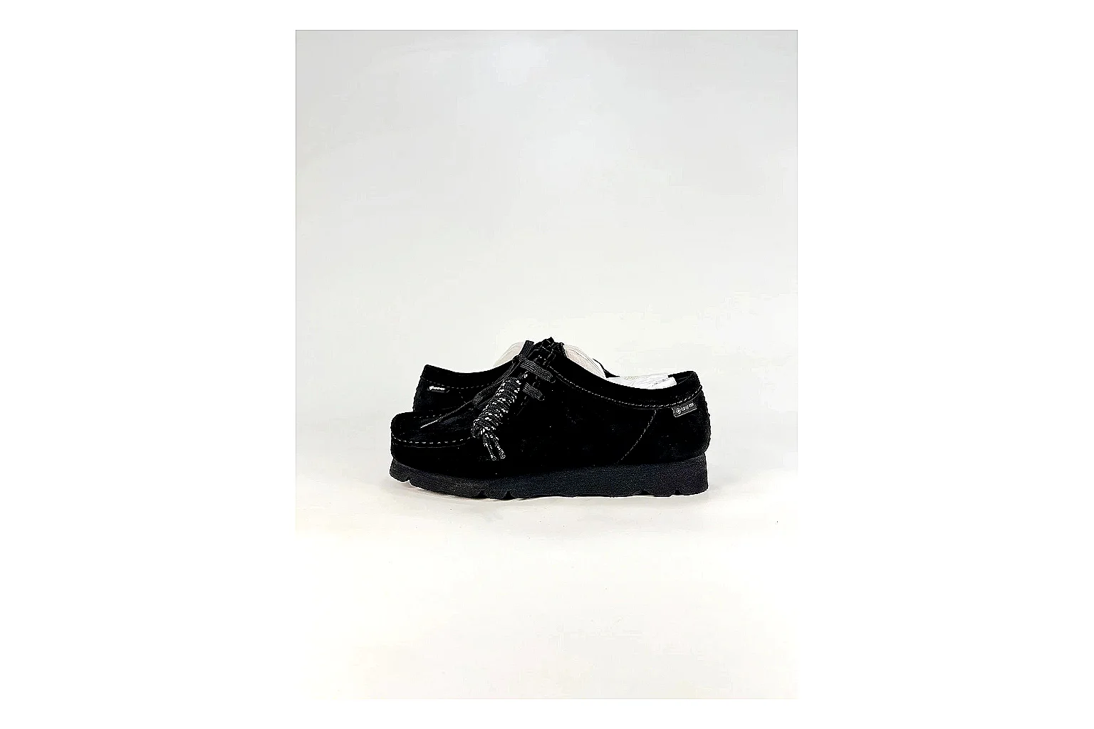 Clarks Wallabee Black Sneakers shopping brief image showing black suede Wallabee shoes with suede texture, side-profile shape, upper panel lines, and outsole detail