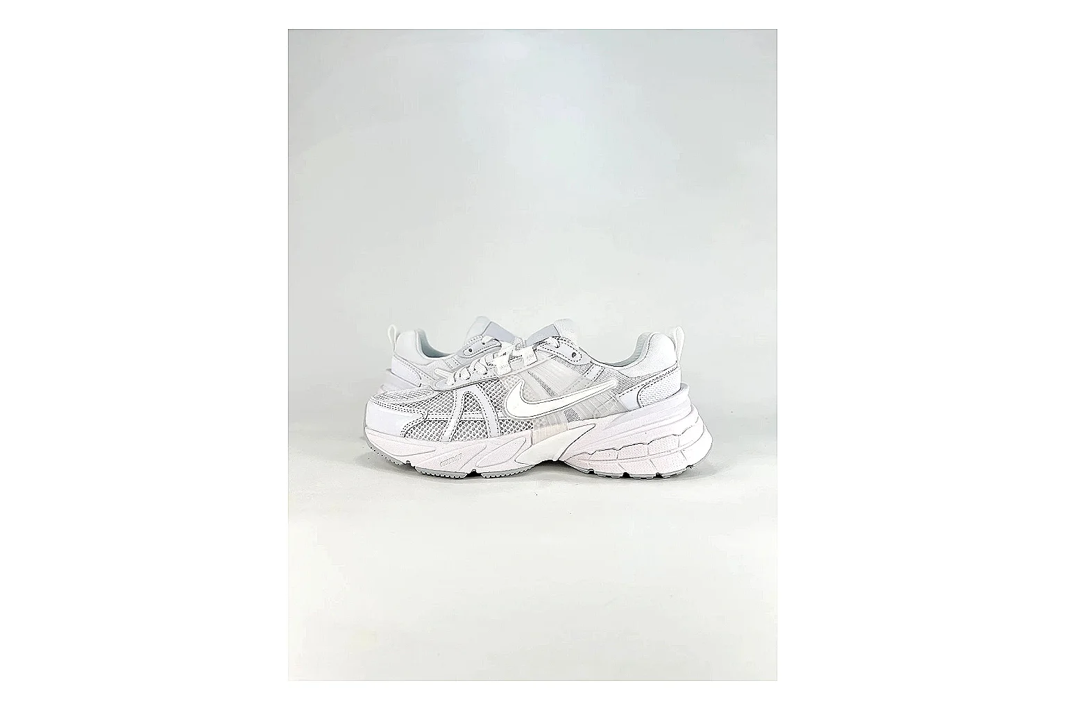 Nike V2K Run White Sneakers shopping brief image showing white retro runner sneakers with mesh-leather texture, side-profile shape, upper panel lines, and outsole detail